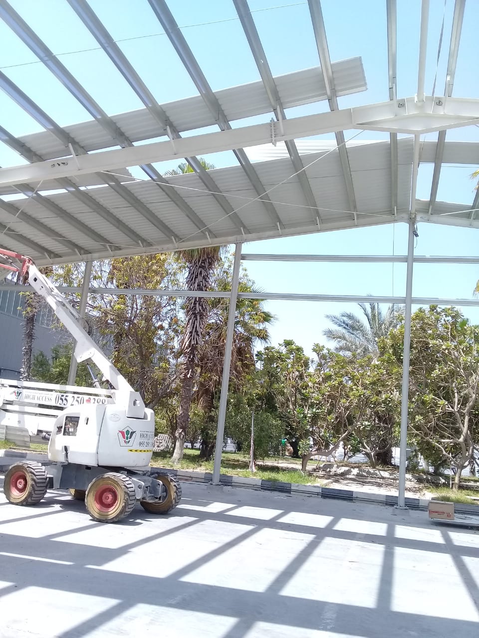 Outdoor steel canopy under construction with man-lift